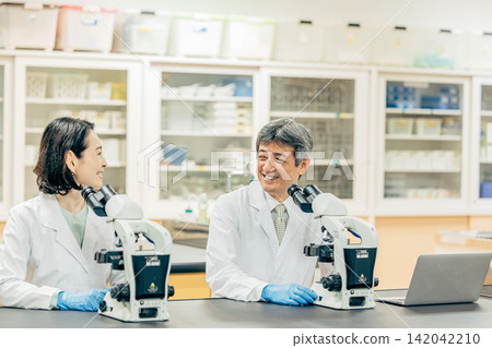 在實驗室中使用顯微鏡進行研究的研究人員 在實驗室中使用顯微鏡進行研究的研究人員 142042210