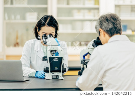 在實驗室中使用顯微鏡進行研究的研究人員 在實驗室中使用顯微鏡進行研究的研究人員 142042215