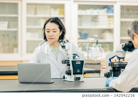 Researchers who conduct research using microscopes in the laboratory Researchers who conduct research using microscopes in the laboratory 142042216