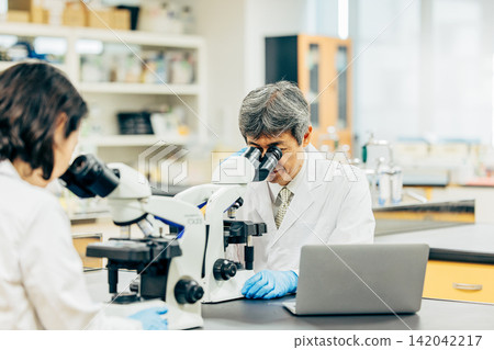 Researchers who conduct research using microscopes in the laboratory Researchers who conduct research using microscopes in the laboratory 142042217