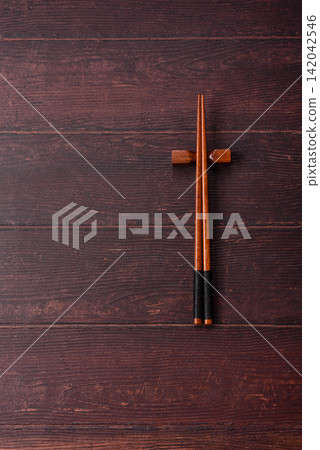 Asian style chopsticks on a dark, empty wooden table. Chopsticks as a food background Asian style chopsticks on a dark, empty wooden table. Chopsticks as a food background 142042546
