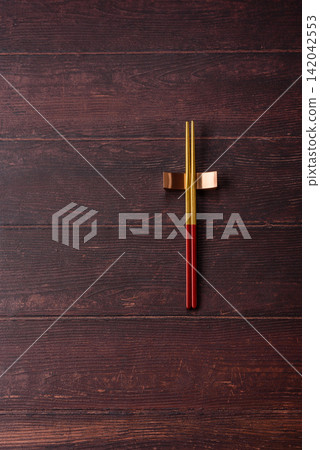 Asian style chopsticks on a dark, empty wooden table. Chopsticks as a food background Asian style chopsticks on a dark, empty wooden table. Chopsticks as a food background 142042553