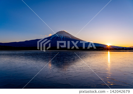 [Shizuoka Prefecture] Mount Fuji seen over Lake Tanuki, covered in a thin layer of ice, at sunrise. 142042679