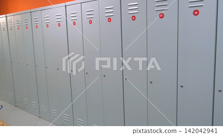 Lockers in in gym fitness locker room or school hallway. Locker row with tiled floor. Gray metal lockers. Hall Interior. No people. Real video. Stainless steel Lockers with number plates for storage. Lockers in in gym fitness locker room or school hallway. Locker row with tiled floor. Gray metal lockers. Hall Interior. No people. Real video. Stainless steel Lockers with number plates for storage. 142042941