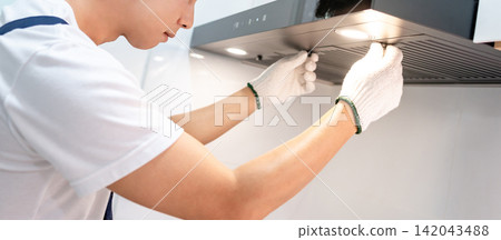 Asian male maintenance worker repairing modern cooker hood in domestic kitchen Asian male maintenance worker repairing modern cooker hood in domestic kitchen 142043488
