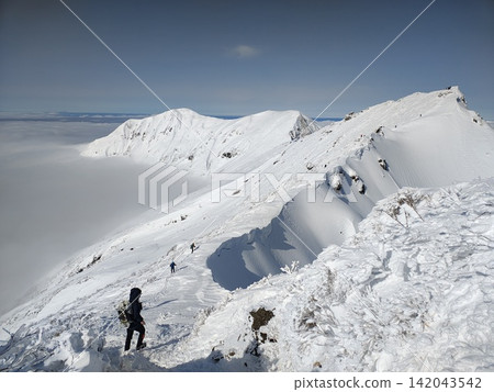Snow-covered mountain climbing and sea of clouds: Climbers traversing snowy ridges in the depths of winter, surrounded by vast and breathtaking scenery. Snow-covered mountain climbing and sea of clouds: Climbers traversing snowy ridges in the depths of winter, surrounded by vast and breathtaking scenery. 142043542