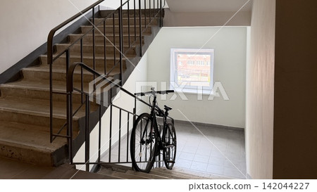 Bicycle parked in apartment building stairwell 142044227