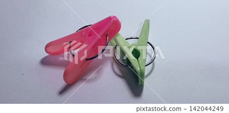 Plastic Clothes Pegs in Pink and Light Green Isolated on White Background Plastic Clothes Pegs in Pink and Light Green Isolated on White Background 142044249