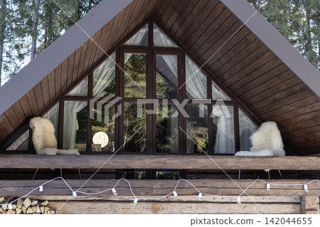 Wooden A frame cabin facade with panoramic glass windows and balcony Wooden A frame cabin facade with panoramic glass windows and balcony 142044655