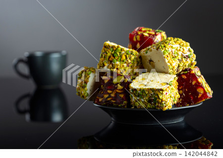 Turkish delights and black coffee on a black reflective background. Turkish delights and black coffee on a black reflective background. 142044842