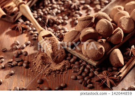 Chocolate truffles and a wooden spoon with cacao powder. Chocolate truffles and a wooden spoon with cacao powder. 142044859