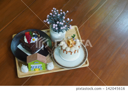 top view macadamia coffee cake and chocolate cake in ceramic plates and vase of pink flowers and decorative on a wooden tray placed on a wooden floor background, food, sweet, copy space top view macadamia coffee cake and chocolate cake in ceramic plates and vase of pink flowers and decorative on a wooden tray placed on a wooden floor background, food, sweet, copy space 142045616