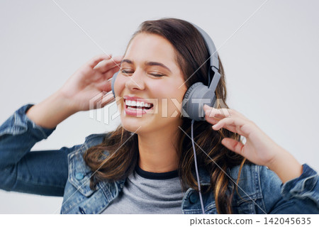 Headphones, dance or happy woman streaming music in studio for singing on grey background to relax. Model, podcast or girl listening to radio playlist, sound or song audio on an online subscription Headphones, dance or happy woman streaming music in studio for singing on grey background to relax. Model, podcast or girl listening to radio playlist, sound or song audio on an online subscription 142045635