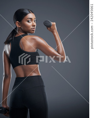 Woman, dumbbells and workout for fitness in studio on grey background for health, muscles and sportswear. Female person, exercise and committed for wellbeing with weights for training and self care Woman, dumbbells and workout for fitness in studio on grey background for health, muscles and sportswear. Female person, exercise and committed for wellbeing with weights for training and self care 142045661
