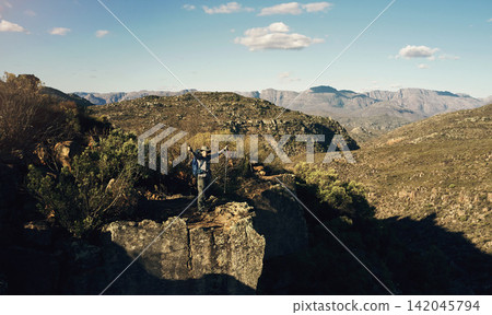 Nature, mountains and person hiking with winning for travel on vacation or holiday with camping. Freedom, success and tourist trekking and backpacking by rocks for outdoor activity on weekend trip. Nature, mountains and person hiking with winning for travel on vacation or holiday with camping. Freedom, success and tourist trekking and backpacking by rocks for outdoor activity on weekend trip. 142045794