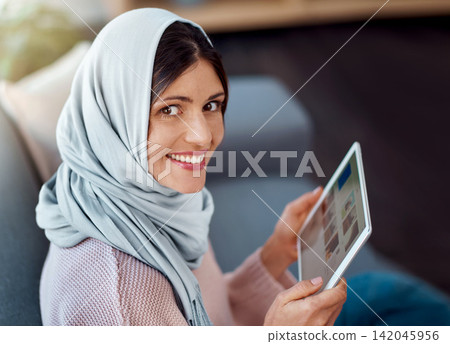 Happy, reading and muslim woman with tablet on sofa for choosing online ebook in living room at home. Relax, digital technology and islamic female person decide on story, novel or literature in house Happy, reading and muslim woman with tablet on sofa for choosing online ebook in living room at home. Relax, digital technology and islamic female person decide on story, novel or literature in house 142045956