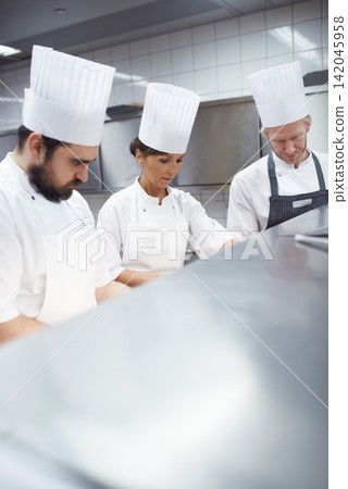 Chef, staff and working in professional kitchen, restaurant and gourmet meal prep and cooking together. Catering service, employee and culinary skills collaboration, hospitality industry and people Chef, staff and working in professional kitchen, restaurant and gourmet meal prep and cooking together. Catering service, employee and culinary skills collaboration, hospitality industry and people 142045958