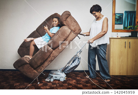 Grandma, boy and vacuum in home portrait, play games and lazy to clean for housework. Grandparent, grandson and bonding for hygiene or responsible housekeeping, dust and routine service for care Grandma, boy and vacuum in home portrait, play games and lazy to clean for housework. Grandparent, grandson and bonding for hygiene or responsible housekeeping, dust and routine service for care 142045959