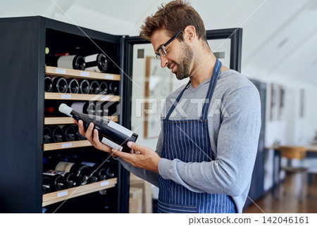 Bottle, cafe and man at wine shelf for selection, choice and luxury hospitality at bistro. Reading, alcohol label and restaurant sommelier, waiter or small business owner checking drinks quality. Bottle, cafe and man at wine shelf for selection, choice and luxury hospitality at bistro. Reading, alcohol label and restaurant sommelier, waiter or small business owner checking drinks quality. 142046161