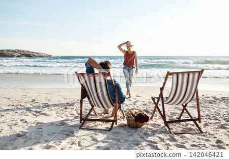 Couple, love and relax on chair at beach for picnic, relationship and walking on sand in nature. Man, woman and romance in summer for vacation, holiday and anniversary on tropical island for date 142046421