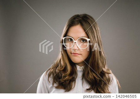 Glasses, hair and portrait of girl nerd in studio on gray background for accessories or fashion. Face, intelligence and vision with cute geek or natural person in eyewear for retro or vintage style 142046505