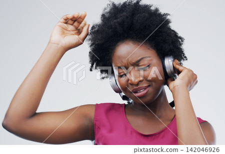 Dancing, music or happy black woman in headphones in studio for singing on grey background. Model, face or African girl listening to radio playlist, sound or podcast audio with afro or subscription Dancing, music or happy black woman in headphones in studio for singing on grey background. Model, face or African girl listening to radio playlist, sound or podcast audio with afro or subscription 142046926