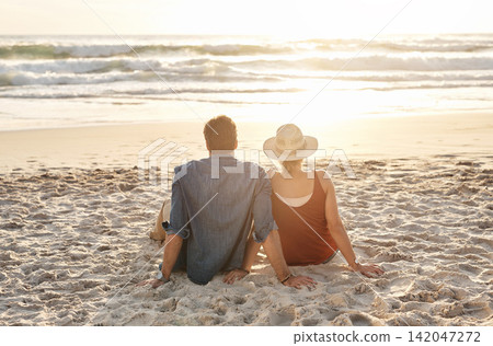Couple, vacation or beach trip sitting on blanket for picnic or relaxing on seashore getaway. Love, man and woman together happy in nature by ocean for romantic date, sunset or holiday in California 142047272