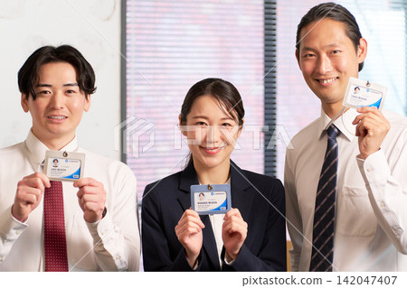 三位商務人士排成一列，面帶微笑，並出示了員工證。 142047407