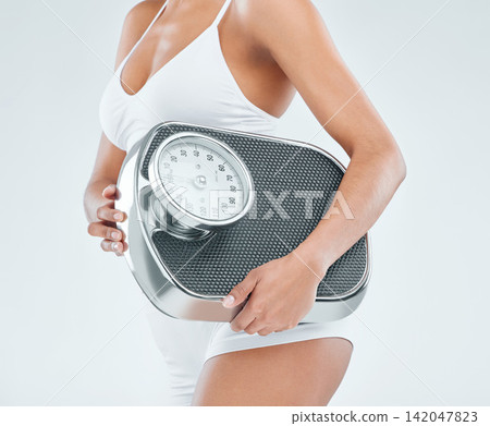 Woman, hands and fitness with scale to lose weight, diet or nutrition on a studio background. Closeup of female person, model or weighing machine for body mass or measure BMI in health and wellness Woman, hands and fitness with scale to lose weight, diet or nutrition on a studio background. Closeup of female person, model or weighing machine for body mass or measure BMI in health and wellness 142047823