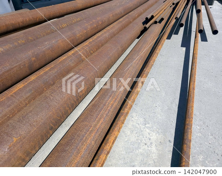 Rusty Round Steel Pipes Resting on a Concrete Surface in an Open Area Rusty Round Steel Pipes Resting on a Concrete Surface in an Open Area 142047900