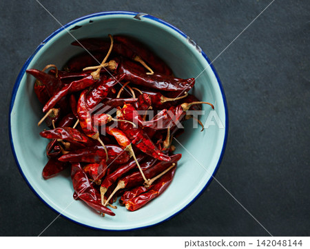 Above, chilli and bowl for pepper, spices and flavor for dry ingredient for cooking, cuisine and food. Paprika, cayenne or condiment and spicy with red colour for capsicum and heat in dish or meal Above, chilli and bowl for pepper, spices and flavor for dry ingredient for cooking, cuisine and food. Paprika, cayenne or condiment and spicy with red colour for capsicum and heat in dish or meal 142048144