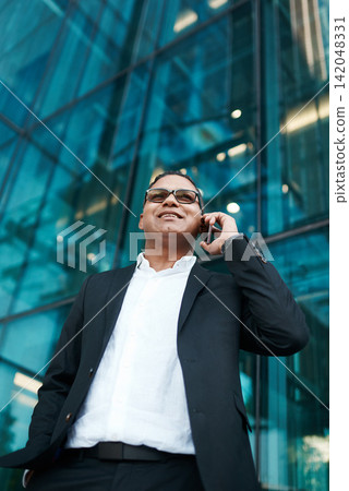 Phone call, building or businessman in city or low angle for project in conversation or communication. Broker, outdoor or mature financial manager networking for investment deal or listening to news Phone call, building or businessman in city or low angle for project in conversation or communication. Broker, outdoor or mature financial manager networking for investment deal or listening to news 142048331