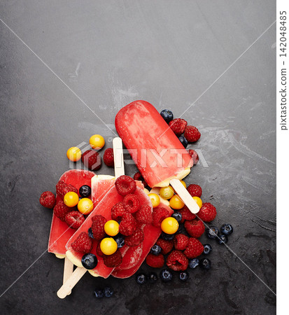 Popsicles, blueberries and fruit for tasty summer treat, snack or frozen dessert in studio background. Fresh, ice lolly and collection of food on counter top for nutrition, diet and yummy eating 142048485