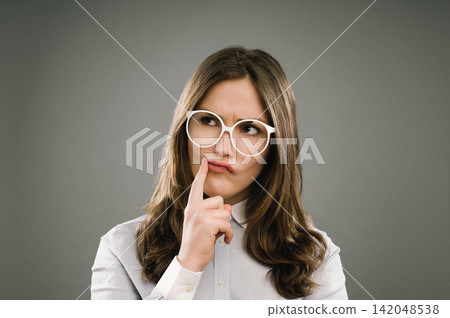 Woman, student and thinking with glasses in studio for education, exam or assessment by background. Girl, nerd or person with ideas, confused and vision for studying, test and college for learning Woman, student and thinking with glasses in studio for education, exam or assessment by background. Girl, nerd or person with ideas, confused and vision for studying, test and college for learning 142048538