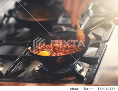 Cooking, food and person with pan in kitchen on heat for meal prep for dinner, supper and lunch in home. Recipe, stove and hands with utensils with ingredients for wellness, nutrition and eating Cooking, food and person with pan in kitchen on heat for meal prep for dinner, supper and lunch in home. Recipe, stove and hands with utensils with ingredients for wellness, nutrition and eating 142048557