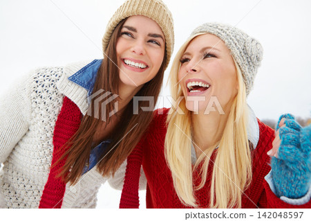 Snow, happy and girl friends outdoor in winter on fun vacation, adventure or holiday. Travel, smile and young women with laughing and bonding together in cold weather on weekend trip in nature Snow, happy and girl friends outdoor in winter on fun vacation, adventure or holiday. Travel, smile and young women with laughing and bonding together in cold weather on weekend trip in nature 142048597