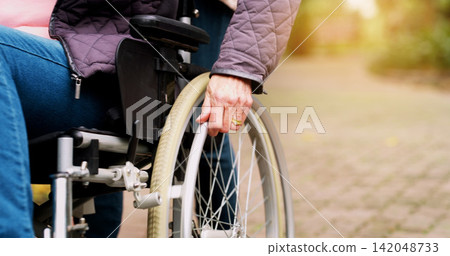 Park, wheelchair and hand of person with a disability for retirement, support and healthcare. Nature, path and elderly man with mobility aid for travel, morning adventure and assistance in garden Park, wheelchair and hand of person with a disability for retirement, support and healthcare. Nature, path and elderly man with mobility aid for travel, morning adventure and assistance in garden 142048733
