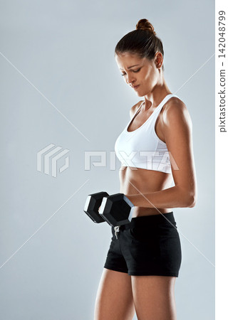 Challenge, dumbbell and weightlifting with woman, exercise in studio and muscle training isolated on grey background. Fitness, strong athlete and heavy equipment for workout with body and power Challenge, dumbbell and weightlifting with woman, exercise in studio and muscle training isolated on grey background. Fitness, strong athlete and heavy equipment for workout with body and power 142048799