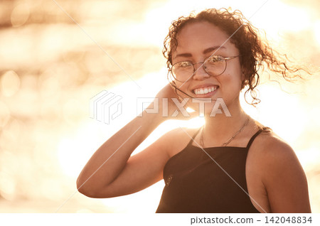 Portrait, beach and travel with woman, sunshine and summer with adventure, smile and vacation. Face, person and girl with joy, seaside and ocean with getaway trip, sunset and journey with break 142048834