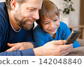 Father and son little boy laughing and using phone. They watching funny videos together, playing games on smartphone. Concept technology, smart phone addicted. Fun weekend activity. Modern fatherhood 142048840