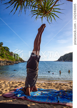 A man doing yoga in headstand pose on Yanui Beach. A man doing yoga in headstand pose on Yanui Beach. 142048895