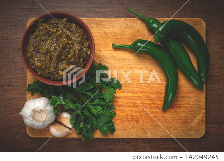green adjika, in a clay bowl, Georgian sauce, with ingredients on a wooden board, top view, no people, green adjika, in a clay bowl, Georgian sauce, with ingredients on a wooden board, top view, no people, 142049245