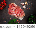 Sliced ham, on a dark background, with cherry tomatoes, and green giant olives, top view, no people, 142049260