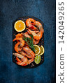 Freshly frozen shrimp, with lemon and rosemary, on black slate, close-up, top view, no people 142049265