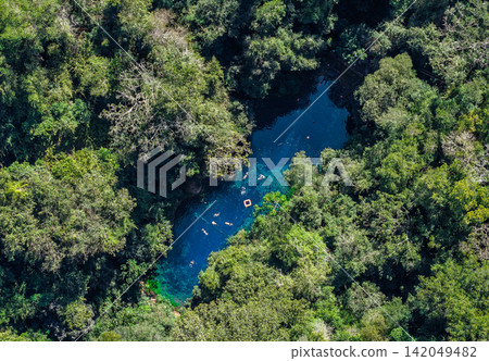 Aerial view of Lake Misteriosa, surrounded by forest, showing its blue waters and swimmers. Aerial view of Lake Misteriosa, surrounded by forest, showing its blue waters and swimmers. 142049482