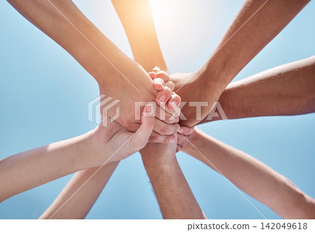 People, teamwork and hands together below for unity, collaboration or synergy on a blue sky background. Closeup or low angle of group or community in trust or solidarity for care, support or mission 142049618