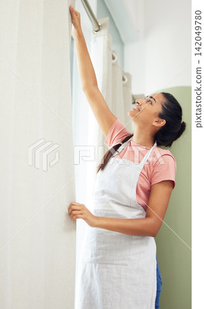 Woman, happy and hanging curtains in home for spring cleaning, housework or hygiene with diy. Housewife, person and window drapes in living room with smile, apron or housekeeping for domestic routine Woman, happy and hanging curtains in home for spring cleaning, housework or hygiene with diy. Housewife, person and window drapes in living room with smile, apron or housekeeping for domestic routine 142049780