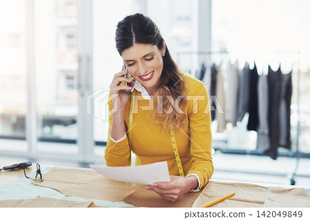 Fashion, business and woman with phone call to client for logistics and planning order shipping. Tailor, client and contact stock warehouse for manufacturing info or chat with employee in workshop Fashion, business and woman with phone call to client for logistics and planning order shipping. Tailor, client and contact stock warehouse for manufacturing info or chat with employee in workshop 142049849