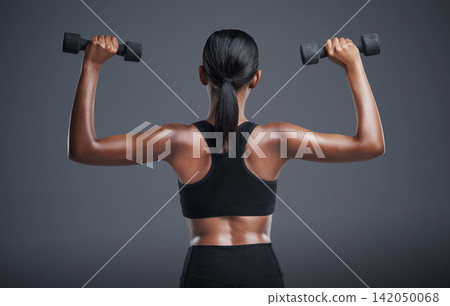 Woman, back and dumbbells in studio for arms, athlete for wellness and weight lifting exercise for power. Strong, Indian bodybuilder and health training, muscle and with equipment on background Woman, back and dumbbells in studio for arms, athlete for wellness and weight lifting exercise for power. Strong, Indian bodybuilder and health training, muscle and with equipment on background 142050068