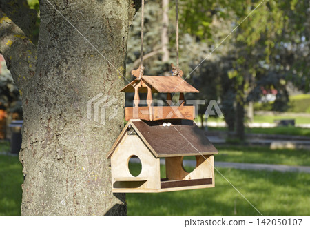 A bird feeder in the shape of a house made of wooden blocks A bird feeder in the shape of a house made of wooden blocks 142050107